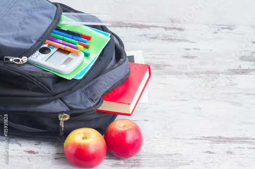 School backpack with supplies and apples on white desktop photo