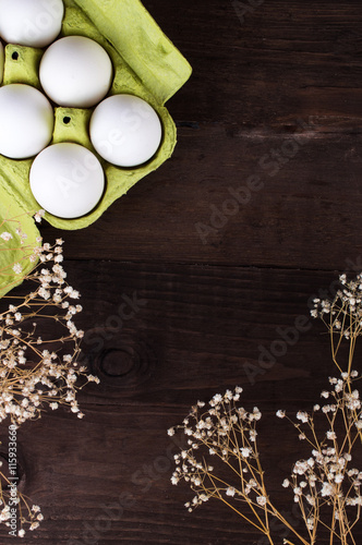 Chicken eggs in a cardboard tray open on a dark wooden background.