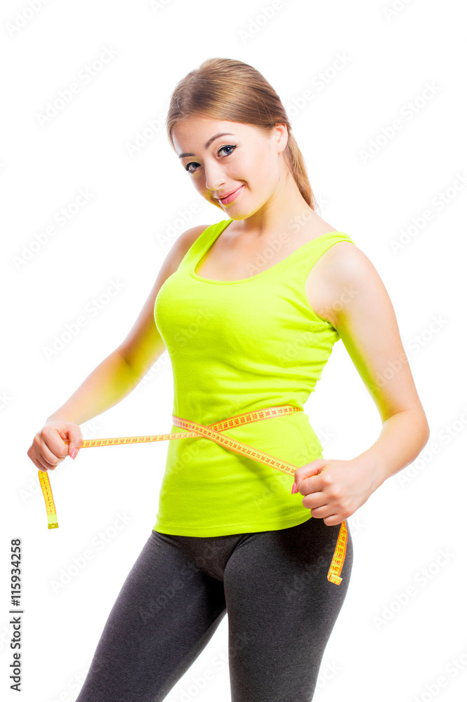 Young smiling woman in sportswear measuring her waist measure tape, isolated on white background. Young smiling woman in sportswear measuring her waist measure tape, isolated on white background.