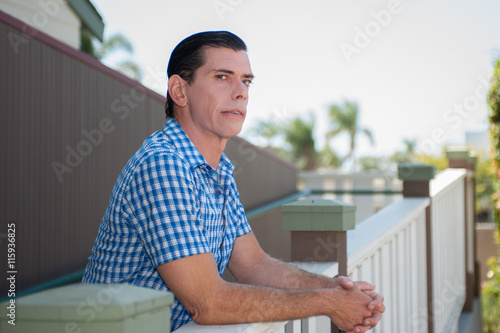 Middle age man resting elbows on handrail.