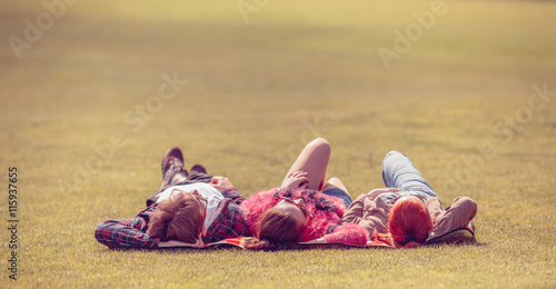 People in sunglasses resting in park. Picnic concept. Picture of best friends lying on picnic rug and looking in blue sky and white clouds.