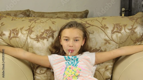 Little girl beautiful looking at the camera while holding a candy in his mouth