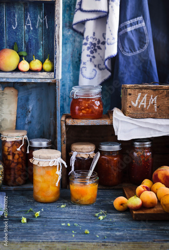 Canning fruts jam and jelly jars over wooden shelf with varities fruits. 