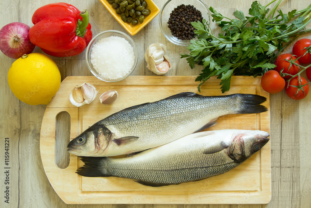 Fresh seabass on a wooden board with fresh vegetables Fresh seabass on a wooden board with fresh vegetables