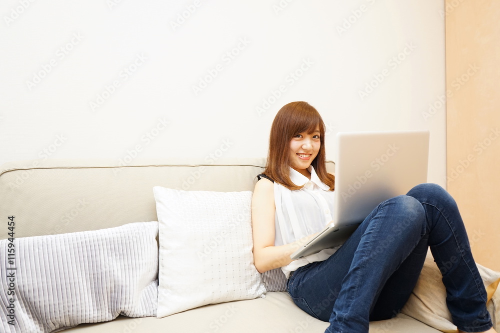 Young japanese woman using a computer on the sofa ソファーでリラックスしてパソコンを使う若い日本人の女性 Young japanese woman using a computer on the sofa ソファーでリラックスしてパソコンを使う若い日本人の女性