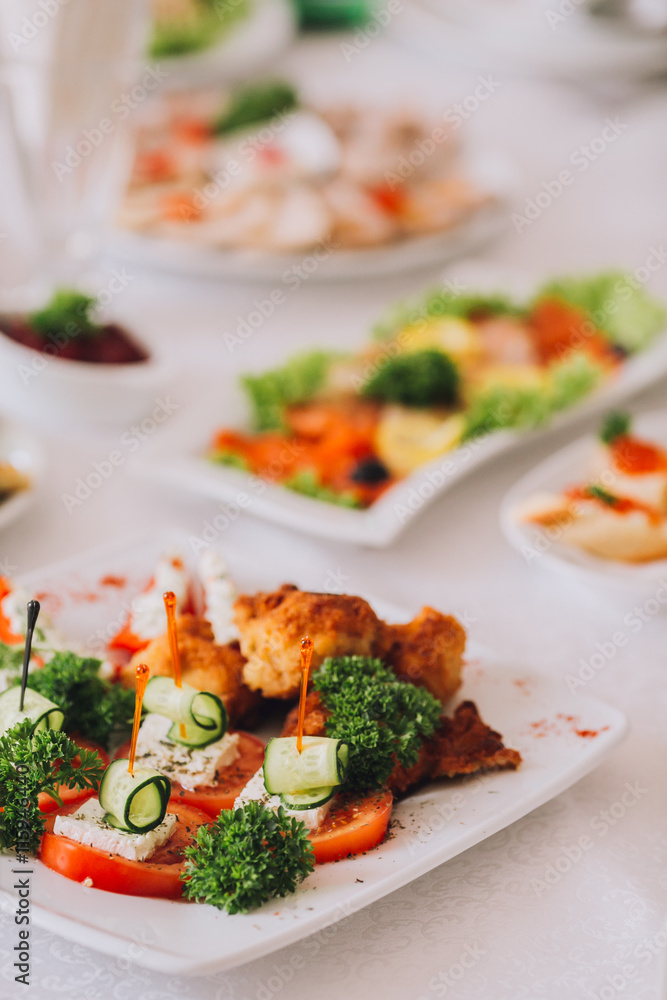 Beautifully decorated catering banquet table with different food snacks and appetizers with sandwich, caviar, fresh fruits on corporate christmas birthday party event or wedding celebration