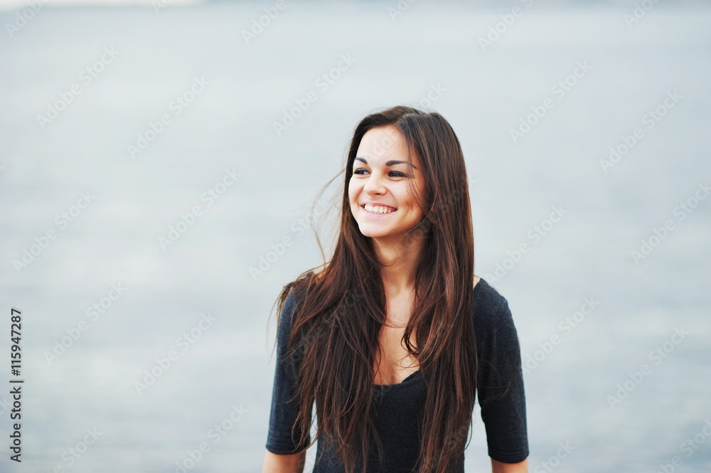 Young beautiful long-haired brunette in the dark blouse is laughing with closed eyes summer clear day. Young beautiful long-haired brunette in the dark blouse is laughing with closed eyes summer clear day.