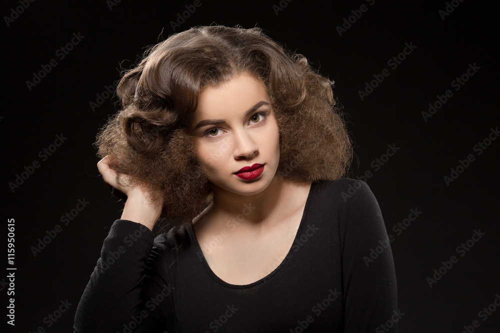 Beautiful lady with modern hairstyle posing isolated on black background. Pretty woman in black dress touching her gorgeous hair. Beautiful lady with modern hairstyle posing isolated on black background. Pretty woman in black dress touching her gorgeous hair.