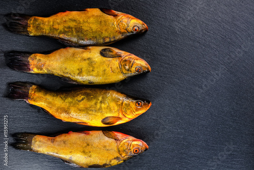 flat lay of fresh tench fish on slate background, close up