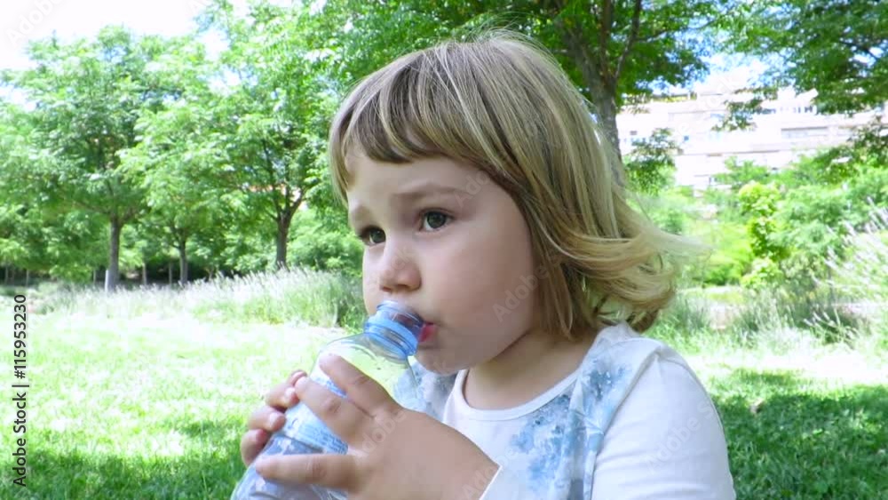 little blonde cute kid sitting on grass at urban park drinking water from plastic bottle in hands
little blonde cute kid sitting on grass at urban park drinking water from plastic bottle in hands