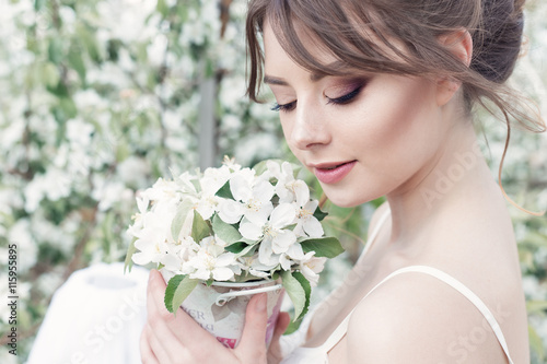portrait of a beautiful sexy cute girl bride in a white dress with delicate make-up and hairstyle of the evening with a bunch of delicate flowers garden
