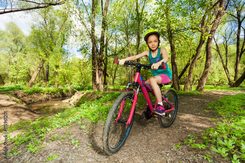 Young girl cycling mountain bike on forest trail