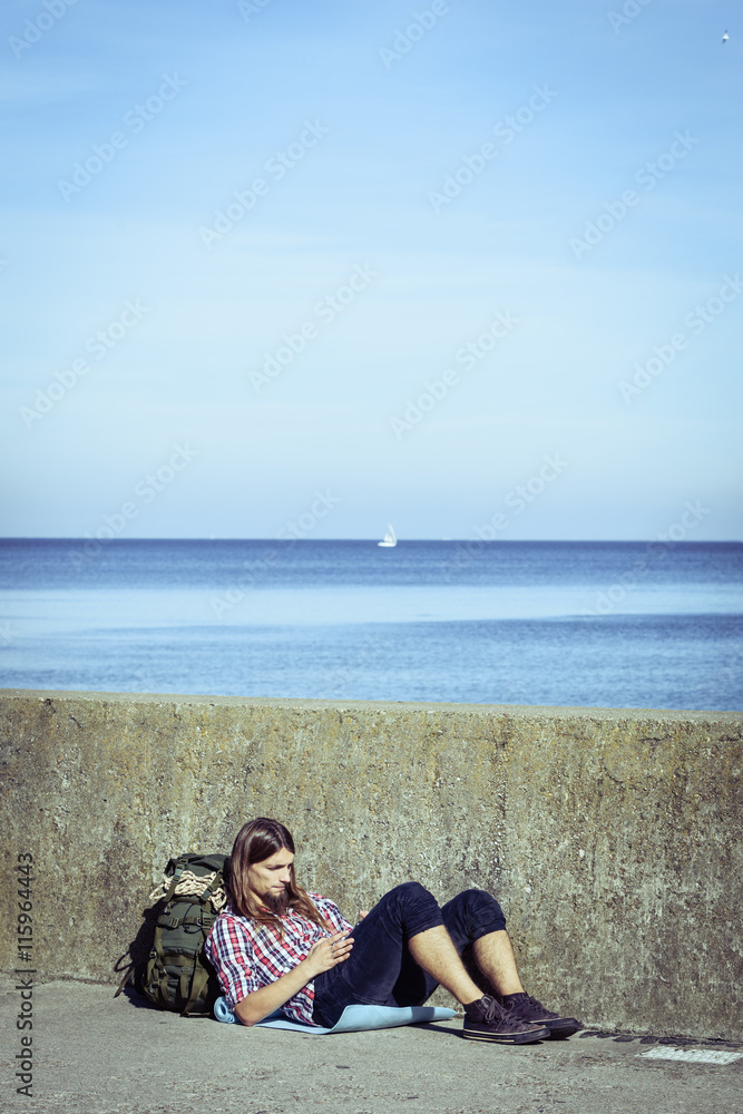 Fototapeta premium Man tourist backpacker sitting with tablet outdoor