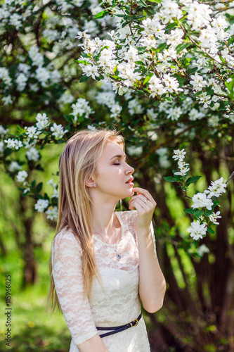 Young beautiful blonde woman in blooming garden. Bride. Closed eyes.