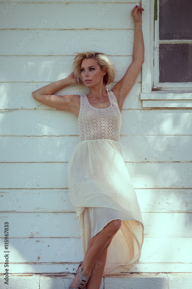 Fototapeta premium Beautiful blonde girl in a white dress in the park