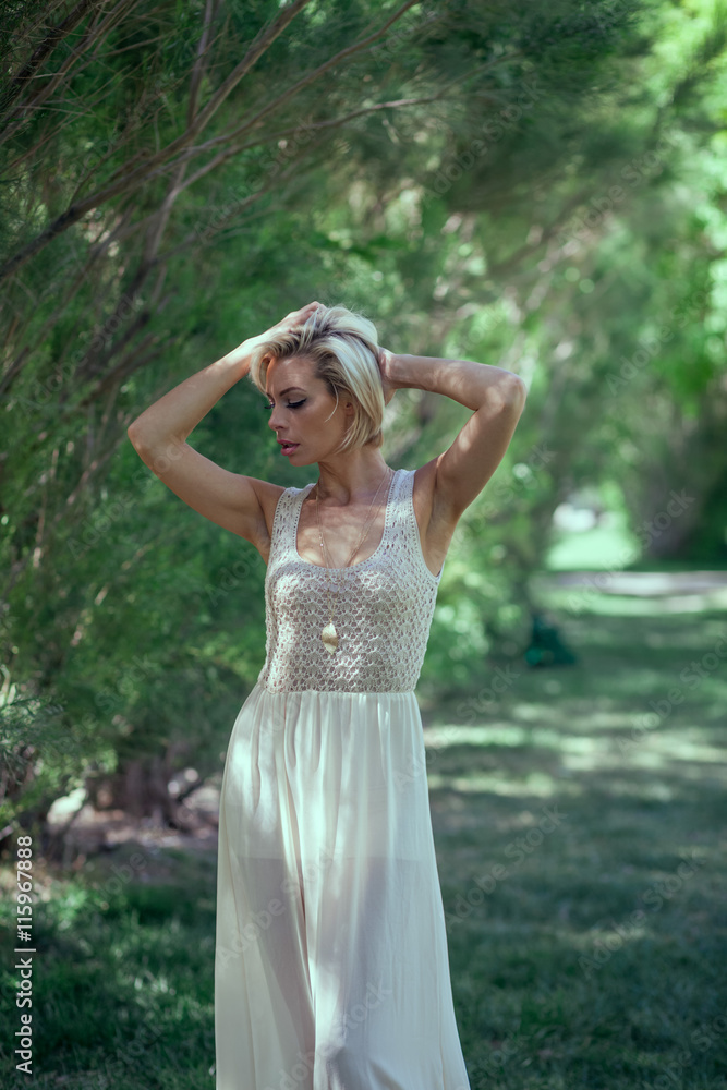Beautiful blonde girl in a white dress in the park Beautiful blonde girl in a white dress in the park