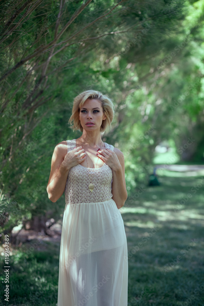 Beautiful blonde girl in a white dress in the park Beautiful blonde girl in a white dress in the park