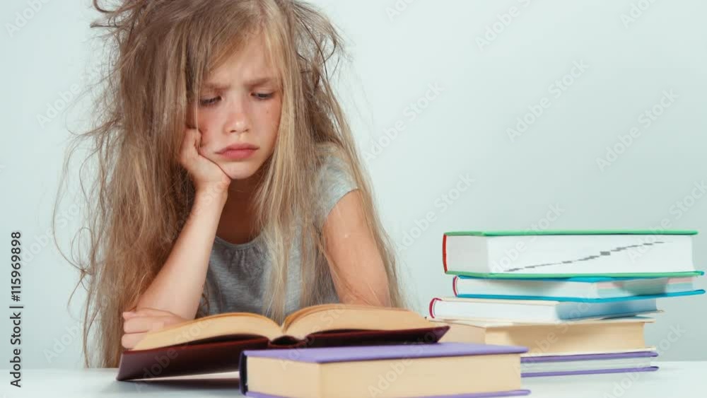Portrait sad schoolgirl does not want to study and read a book. Child isolated on white Portrait sad schoolgirl does not want to study and read a book. Child isolated on white