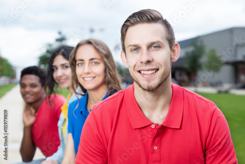 Lachender junger Mann mit Bart mit internationalen Freunden