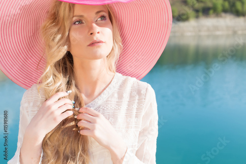 beautiful sweet gentle girl in white dress in light big pink hat on the shore of the blue sea at sunset summer evening sun