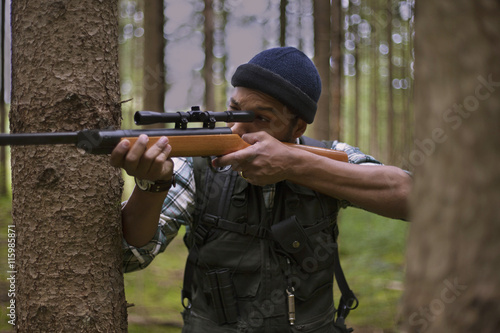 Interracial hunter in the forest aiming at prey