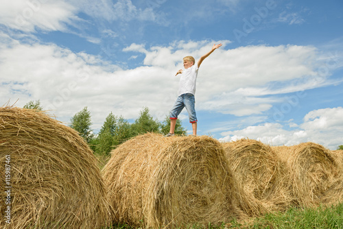Teenager jumps on hay. Happy boy.