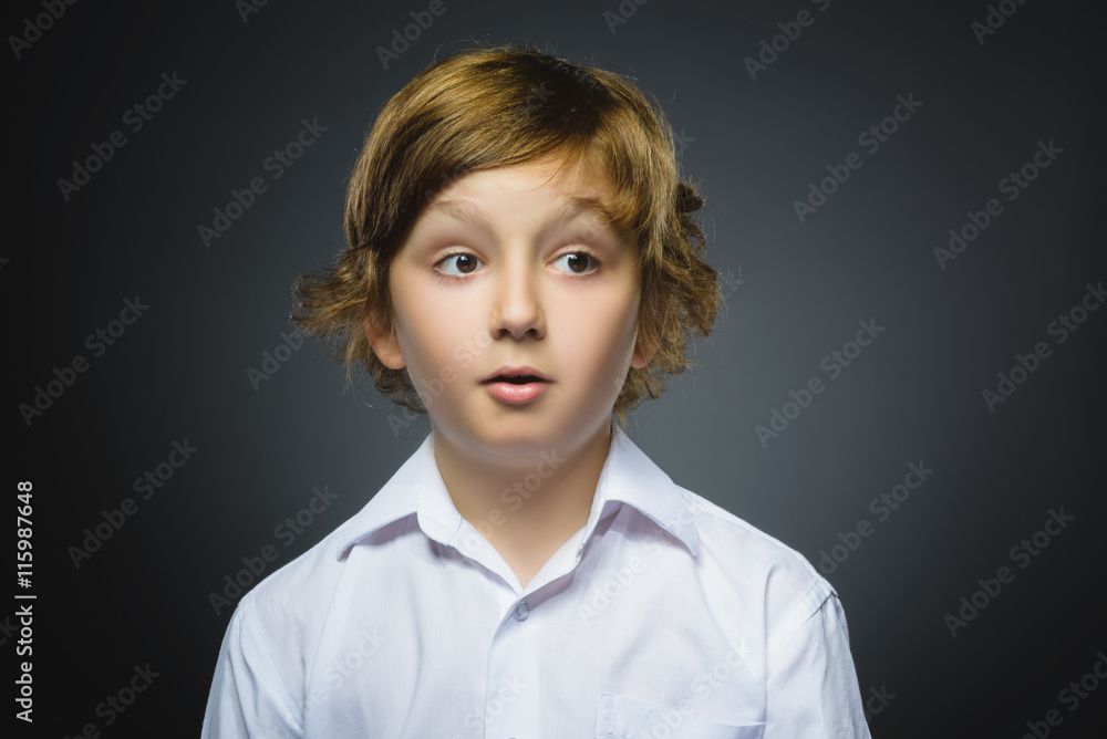 Closeup Portrait of handsome boy with astonished expression while standing against grey background Closeup Portrait of handsome boy with astonished expression while standing against grey background
