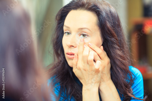 Close up of a woman putting contact lens in eye.