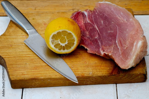 Closeup menin the kitchen is cutting pork on cutting board photo