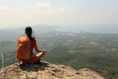young woman backpacker hiking on mountain peak cliff
