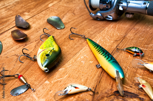 Fishing baits and rod isolated on wooden background