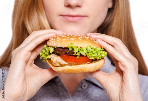 It is so delicious.  Attractive young woman eat hamburger over white background.