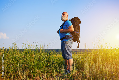 Aged man in good physical shape standing in the grass and carryi
