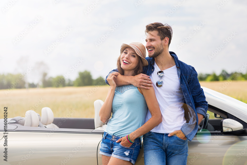 Young couple standing near convertible
