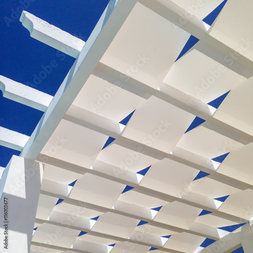 The white material weave of the roof of a pergola. Looking up at a blue summer, Spanish sky. the pergola provides poolside shade. Mobilestock