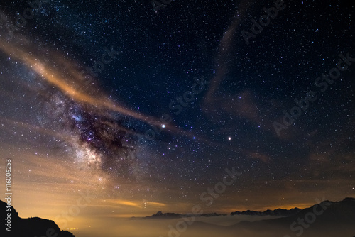 The colorful glowing core of the Milky Way and the starry sky captured at high altitude in summertime on the Italian Alps, Torino Province. Mars and Saturn glowing mid frame.