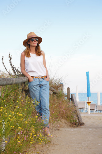 Shot of a beautiful mature woman standing along the seashore. © sepy