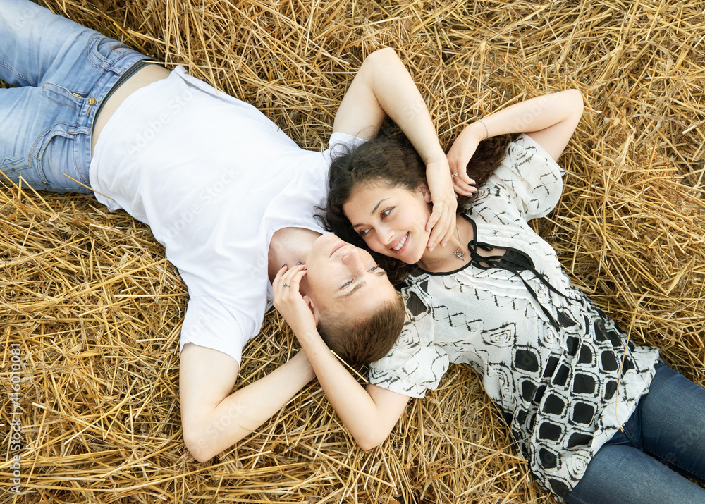 happy young couple lie in straw, wheaten field at evening, romantic people concept, beautiful landscape, summer season happy young couple lie in straw, wheaten field at evening, romantic people concept, beautiful landscape, summer season
