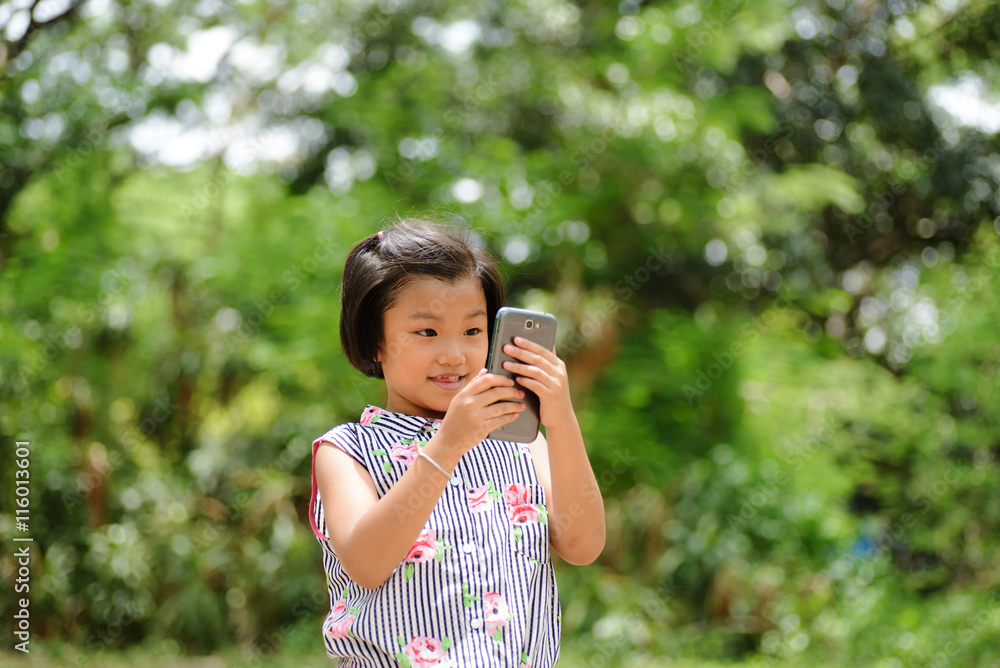 Adorable little girl taking a photo by smartphone against bokeh Adorable little girl taking a photo by smartphone against bokeh