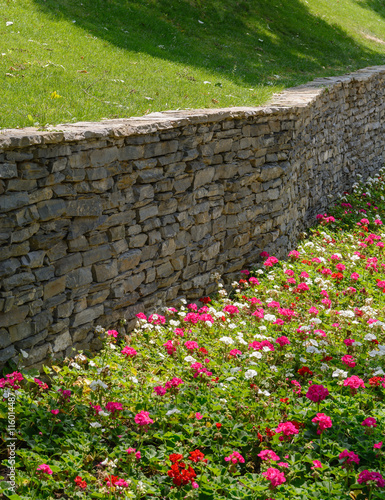 Flowers, green grass and retaining wall gray brick