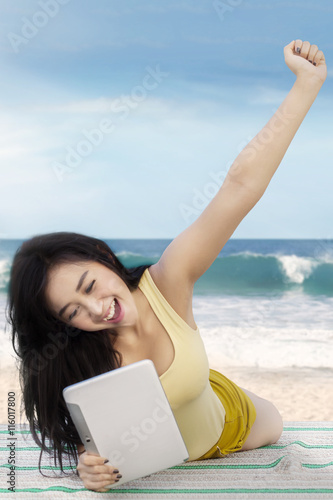 Girl with long hair uses tablet at shore