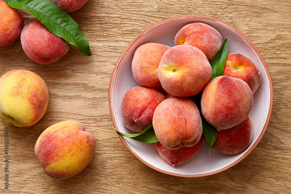 Ripe peaches in a bowl on wooden background Ripe peaches in a bowl on wooden background