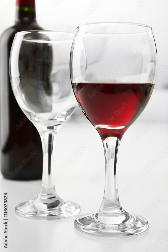 Glass of red wine with bottle on blurred interior background