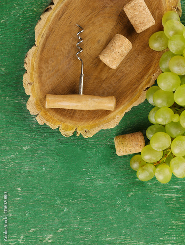 Wine corks and tailspin with bunch of grapes on wooden background photo