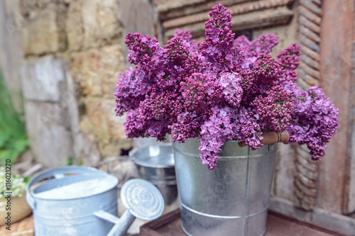 Purple lilac in metal bucket on porch