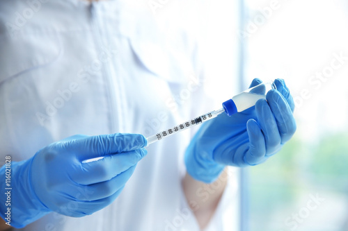 Doctor hands with syringe on light background