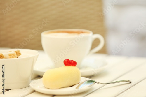 Dessert with red currant and cappuccino on light wooden table