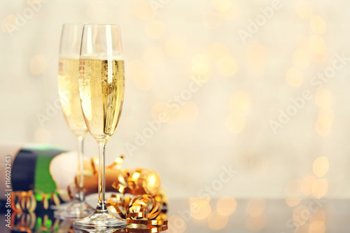 Two champagne glasses and bottle on light background