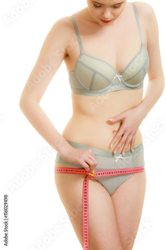 Woman in lingerie measuring her hips with measure tape.