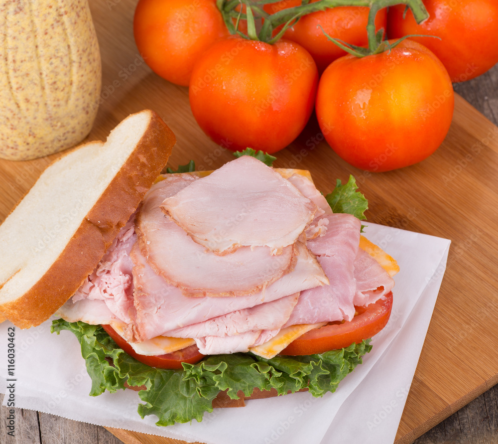 Delicious Ham Sandwich With Tomatoes and Mustard in Background